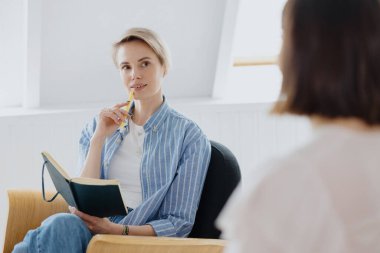 Genç ve güzel bir Avrupalı kadın psikolog veya kısa sarı saçlı bir psikiyatrist bir müşterisiyle terapi yürütür.