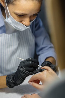 Afrikalı bir kadın Avrupalı bir kadın için manikür yapar. Stüdyoda veya kadınlar için güzellik salonunda manikür işlemi..