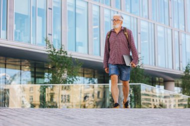 Gömlekli ve dizüstü bilgisayarlı kıdemli bir işadamı büyük bir şirkette kariyer yapıyor.