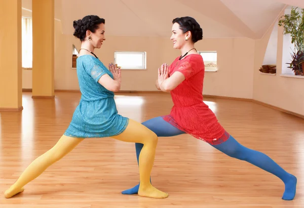 Two young women do yoga indoors — Stock Photo, Image