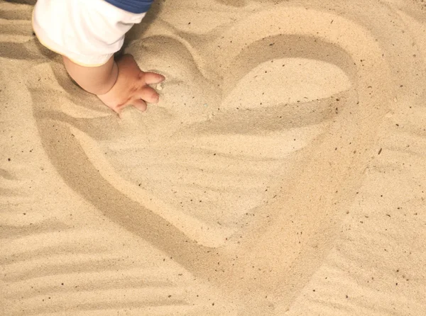 Παιδί που παίζει με την άμμο, αντλώντας μια καρδιά στην άμμο — Φωτογραφία Αρχείου