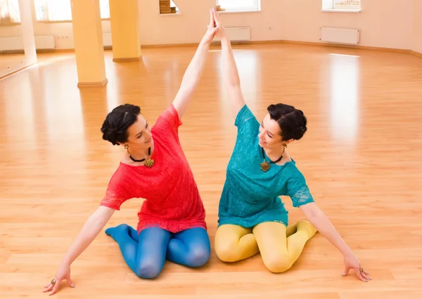 Two young women do yoga indoors — Stock Photo, Image