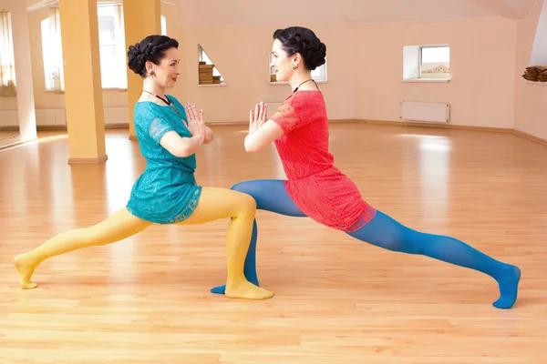 Two young women do yoga indoors — Stock Photo, Image