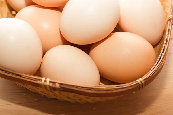 Ahşap bir masa üzerinde bir hasır sepet içinde birçok yumurta — Stok fotoğraf