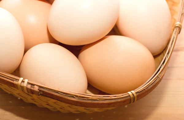 ahşap bir masa üzerinde bir hasır sepet içinde birçok yumurta