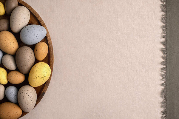Easter holidays flatlay with natural pastel colored eggs on a linen tablecloth