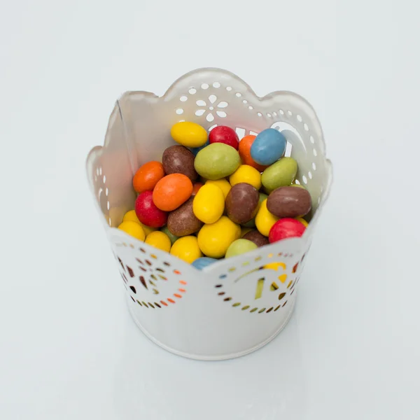 Dulces coloridos en una olla sobre un fondo blanco — Foto de Stock
