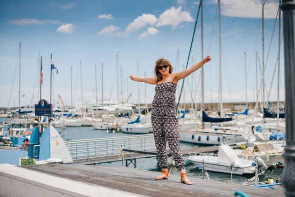 A young pretty girl walking at a port near the moored yachts — Stock Photo, Image