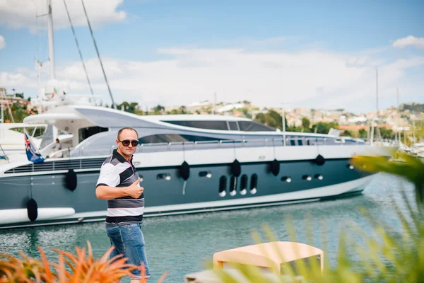 Nice young man walking at a port near the moored yachts — Stock Photo, Image