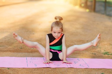 Kız jimnastik egzersiz temiz havada gerçekleştirir.