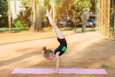 Kız jimnastik egzersiz temiz havada gerçekleştirir.