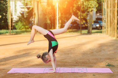 Kız jimnastik egzersiz temiz havada gerçekleştirir.
