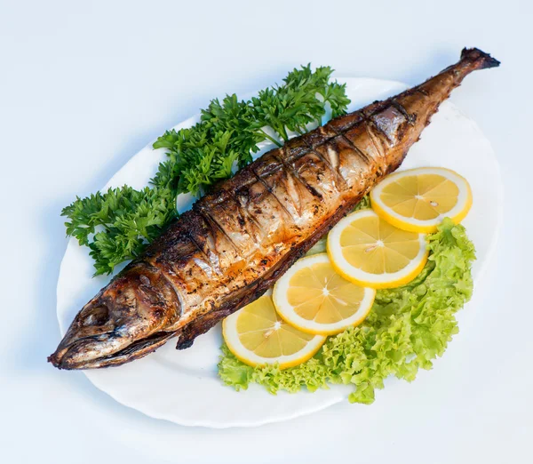 Fish cooked on fire on a white plate with lettuce leaves and par — Stock Photo, Image