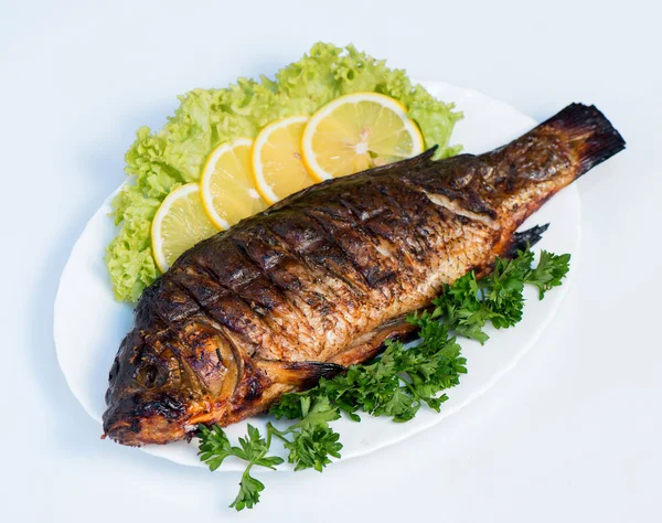 Ryby gotowane w ogniu na białym talerzu z liśćmi sałaty i par — Zdjęcie stockowe