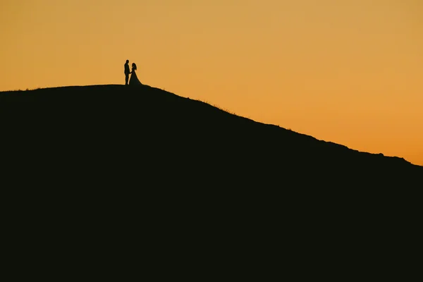 Romantic bride and groom watching sunset — Stock Photo, Image