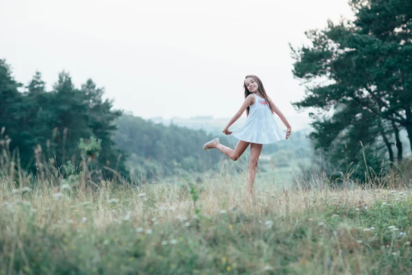 Little cutie girl in a white dress dancing in the woods — Stock Photo, Image