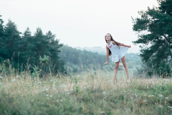 在一条白色的连衣裙，跳舞在树林里的小可爱女孩 — 图库照片