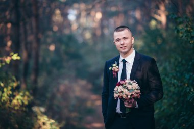 Gülümseyen ve gelin için bekleyen düğün smokin, yakışıklı damat.