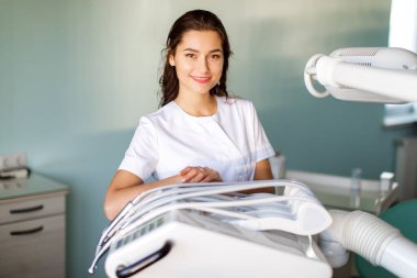 Üniformalı genç bir dişçi ofiste vakit geçirir.