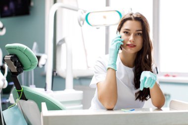 Masasında cep telefonuyla konuşan ciddi bir kadın doktor.