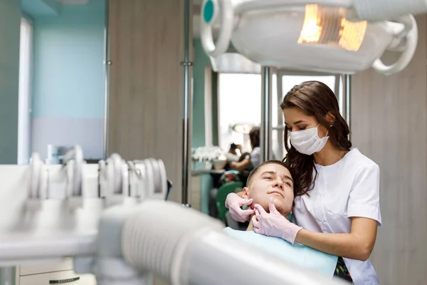 Klinikte Orta Yaşlı Bir Adamın Yanında Duran Genç Kadın Dişçinin — Stok fotoğraf