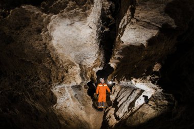 Speleolog, derin, dikey mağara tünelinde ipten iniyor..