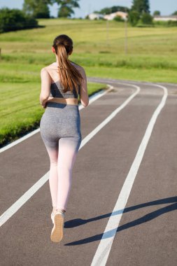 İyi koşu koşucusu kız antrenman için hazırlanıyor stadyum kampüsündeki şerit atletizm pistlerinde koşuyor.