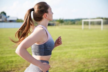 İyi koşu koşucusu kız antrenman için hazırlanıyor stadyum kampüsündeki şerit atletizm pistlerinde koşuyor.
