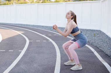 Lastik bantla dışarıda egzersiz yapan genç bir kadın..