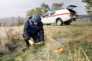 Özel takım elbiseli bir adam dedektörle çalışıyor ve patlayıcı bir cihaz buldu..