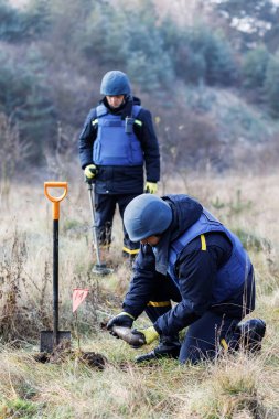 Özel takım elbiseli bir adam dedektörle çalışıyor ve patlayıcı bir cihaz buldu..