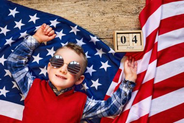 Sevimli ve neşeli bir adam tahta bir arka planda Amerikan bayrağının yanında gözlüklü yatıyor.