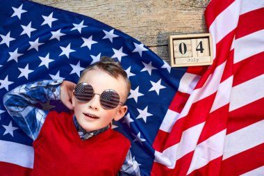 Sevimli ve neşeli bir adam tahta bir arka planda Amerikan bayrağının yanında gözlüklü yatıyor.