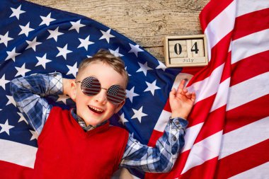 Sevimli ve neşeli bir adam tahta bir arka planda Amerikan bayrağının yanında gözlüklü yatıyor.