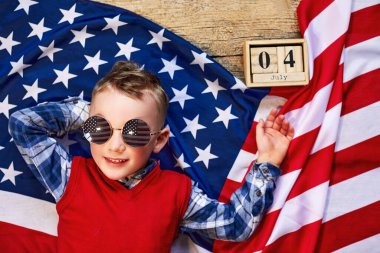 Sevimli ve neşeli bir adam tahta bir arka planda Amerikan bayrağının yanında gözlüklü yatıyor.