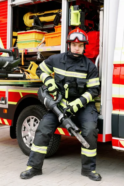 制服姿でヘルメット姿の強い男が救助車のそばに立っていた 救助者だ — ストック写真