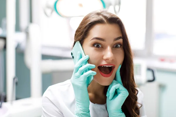 Serious female doctor talking on mobile phone at his desk