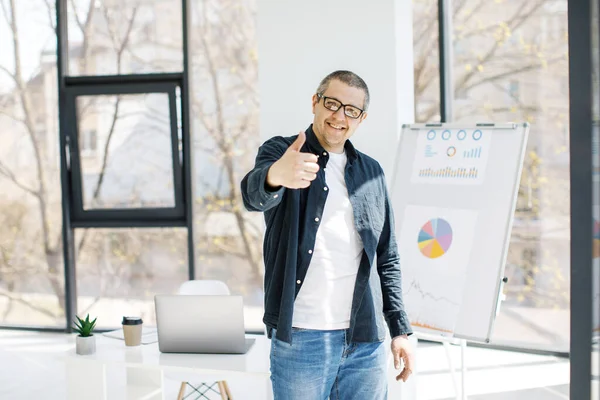 A man, strong physique, dressed in casual clothes works in the office. The man works in a remote place of work