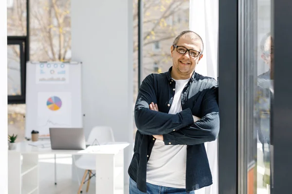 A man, strong physique, dressed in casual clothes works in the office. The man works in a remote place of work