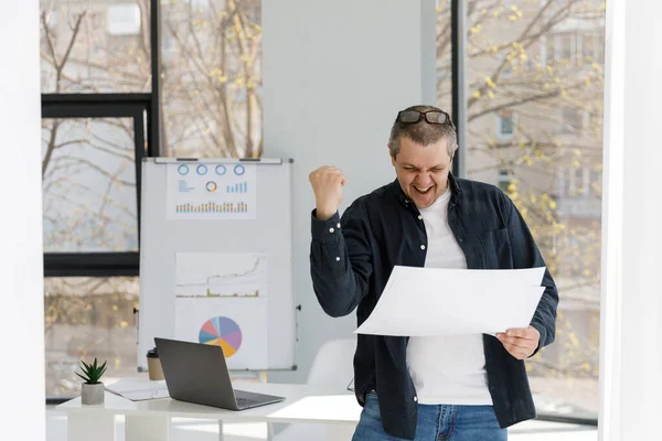 A man dressed in casual style works in the office and looking through business papers. The man works in a remote place of work