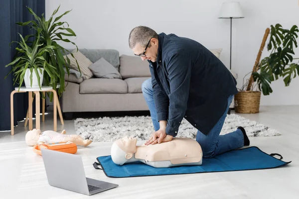 Paramedic demonstrating first aid on manikin during training alone in living room. The instructor showing CPR on training doll