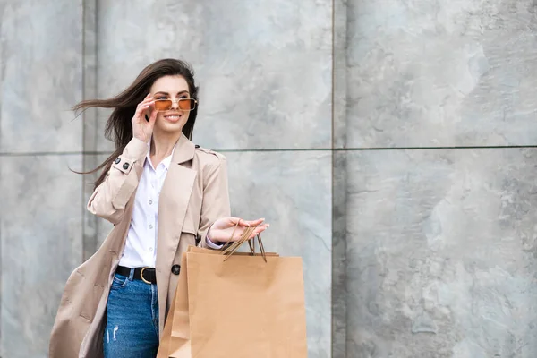 ショッピングバッグやショッピングセンターの近くの購入の多くを持つカジュアルな服の女の子は彼女のパッケージ 消費者販売 人々のコンセプトを笑顔で手 — ストック写真