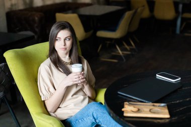 Kafe 'de laptopta çalışan esmer saçlı beyaz bir iş kadını..