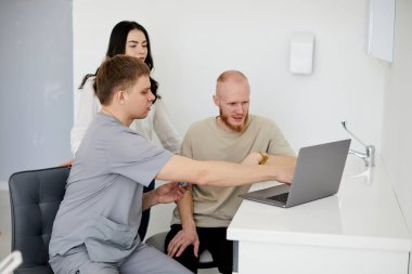 Genç bir dişçi iki hasta için danışmanlık yapıyor..