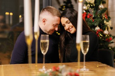 Çift mum ve şampanyayla romantik bir akşam yemeği yiyor, sıcak ve şenlikli bir atmosfer yaratıyor.