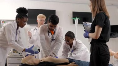 Tıp öğrencileri gözetim altında bir eğitim mankeni üzerinde suni teneffüs yapıyor.