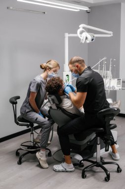 Modern bir diş kliniğinde hastaya ağız hijyeni ve sağlık kontrolü yapan diş hekimleri