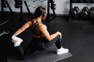 Kadın beden eğitimi dersinde vücut esnetiyor. Portre ve spor hazırlığı. Genç kadın spor salonunda bacağını esnetiyor..