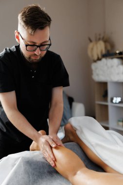 Profesyonel fizyoterapist bir müşteriye rahatlık, vücut bakımı ve rehabilitasyon için elle masaj yapıyor.