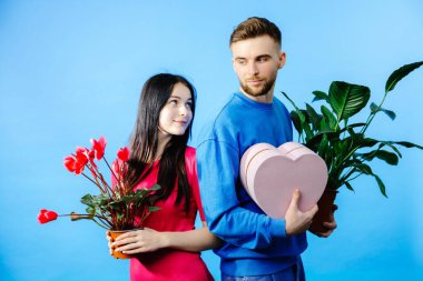 Çiçek saksısı ve kutu taşıyan sevgili ve hediye bekleyen romantik bir sürpriz..